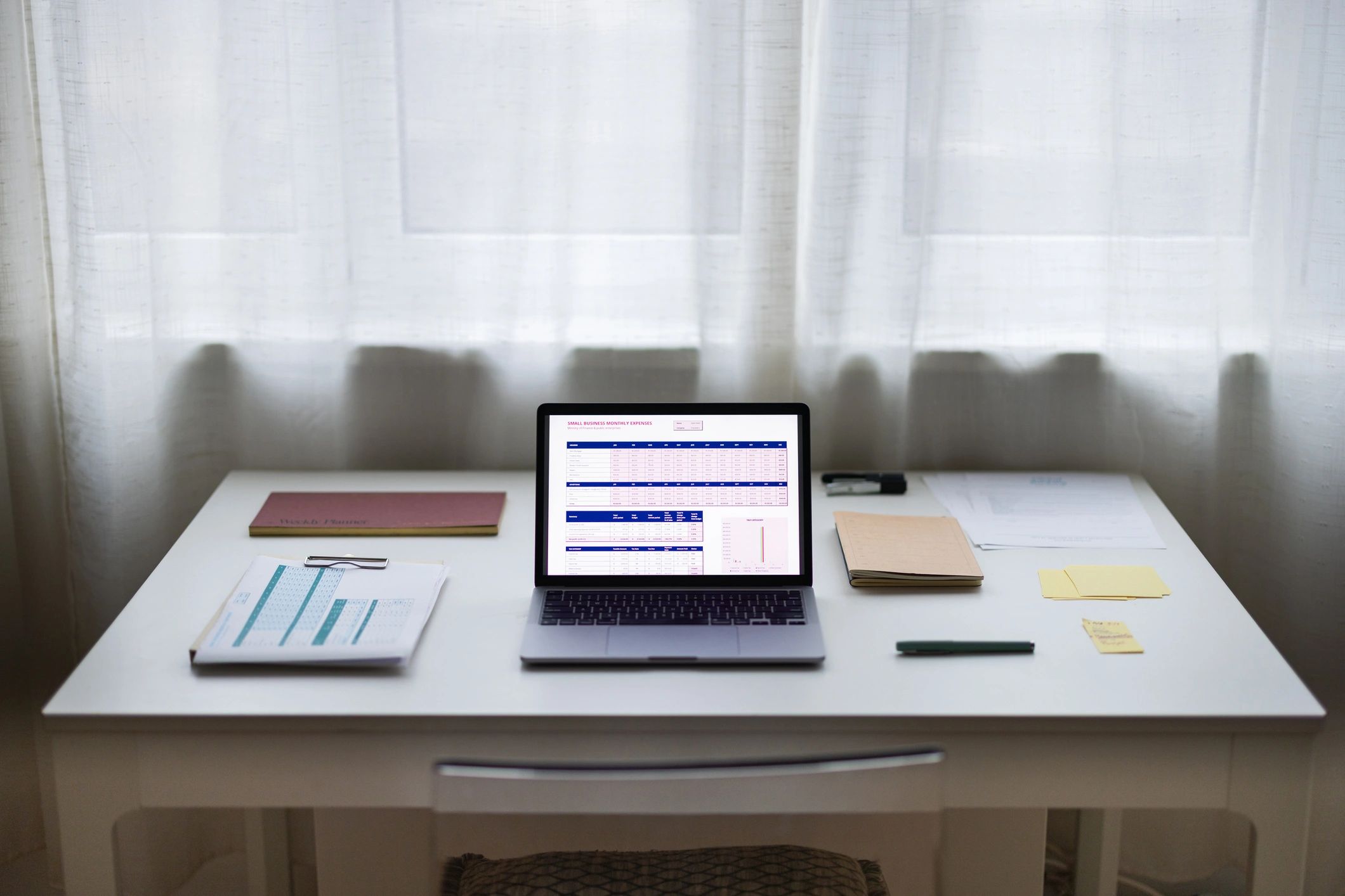 Organized desk with laptop showing charts and paperwork